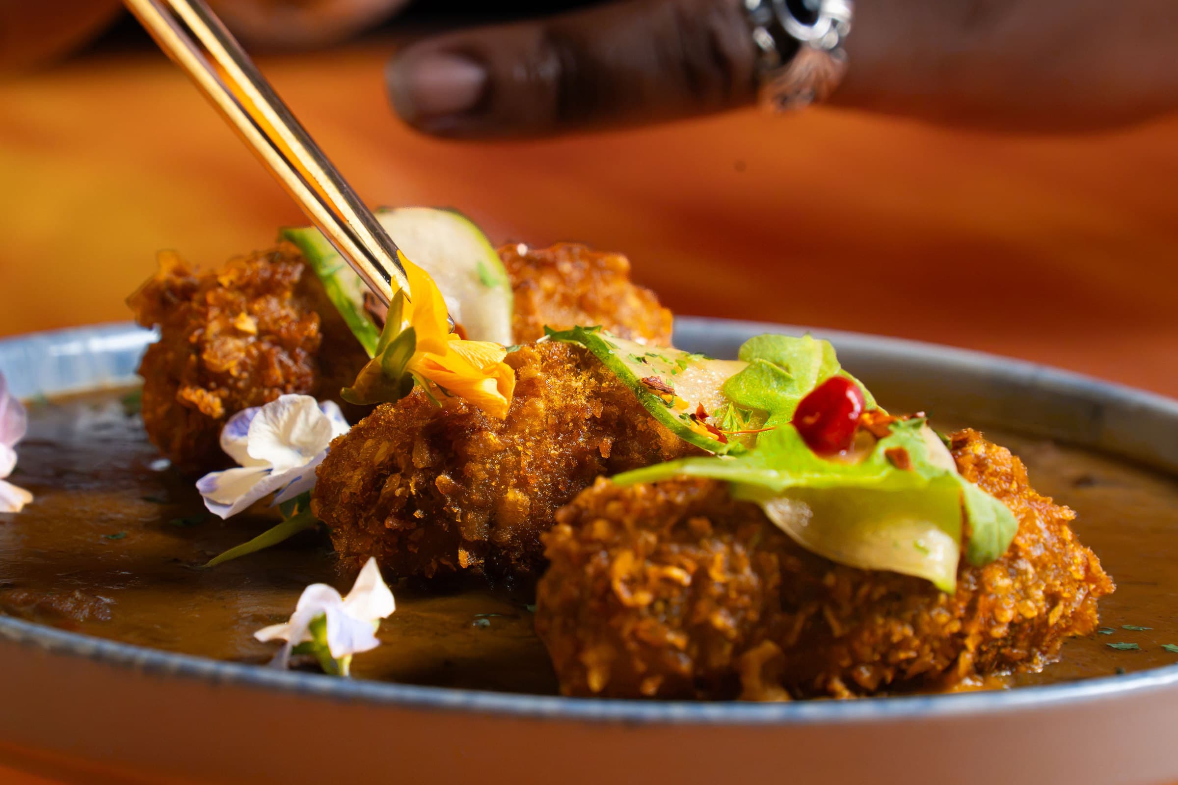 Chef garnishing croquettes with edible flowers